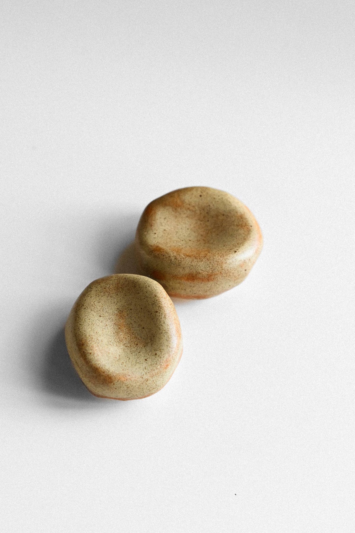 Zwei beige-braun gesprenkelte Sorgensteine mit glasierten Mulden auf hellem Hintergrund.