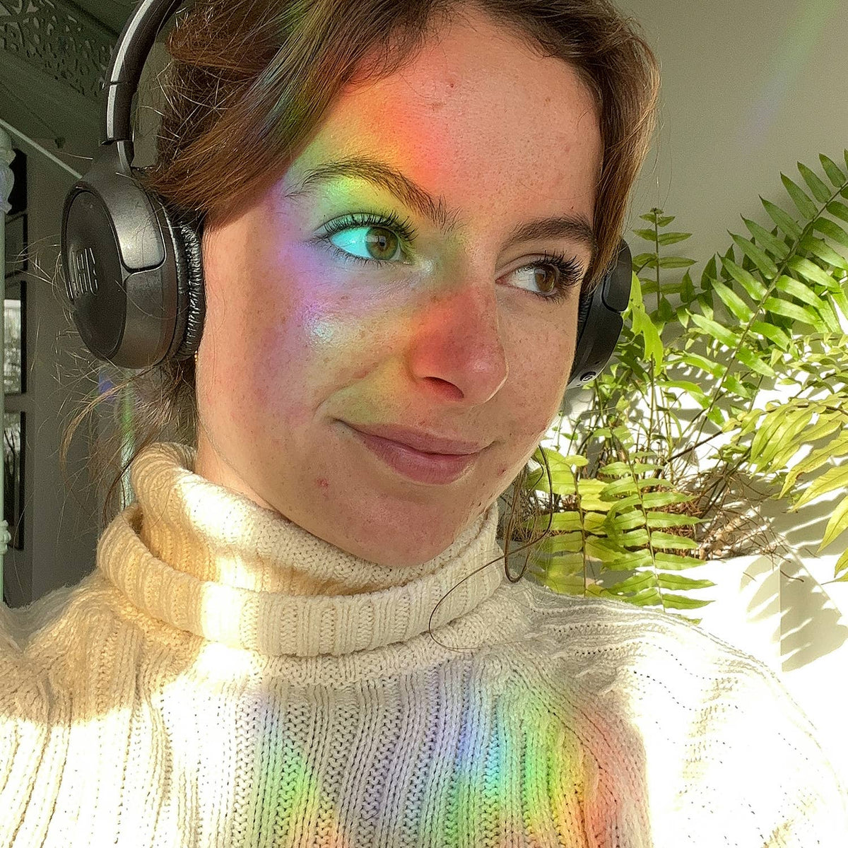 Farbige Lichtreflexe auf dem Gesicht einer Person mit Kopfhörern.